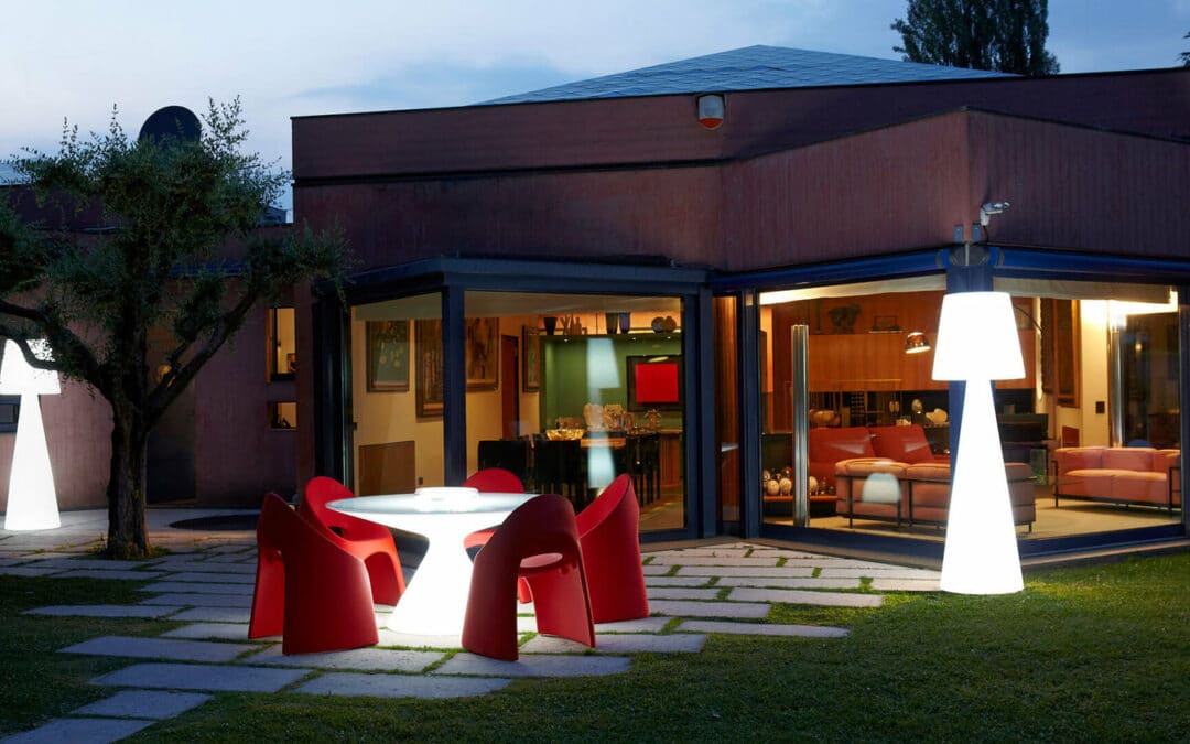 Mobilier lumineux design avec table ronde éclairée et chaises rouges dans aménagement extérieur moderne