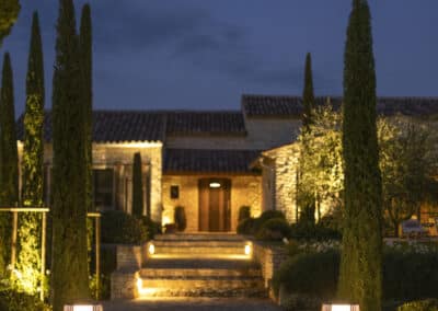 Lanternes d’éclairage de jardin haut de gamme illuminant une allée paysagère menant à une maison en pierre