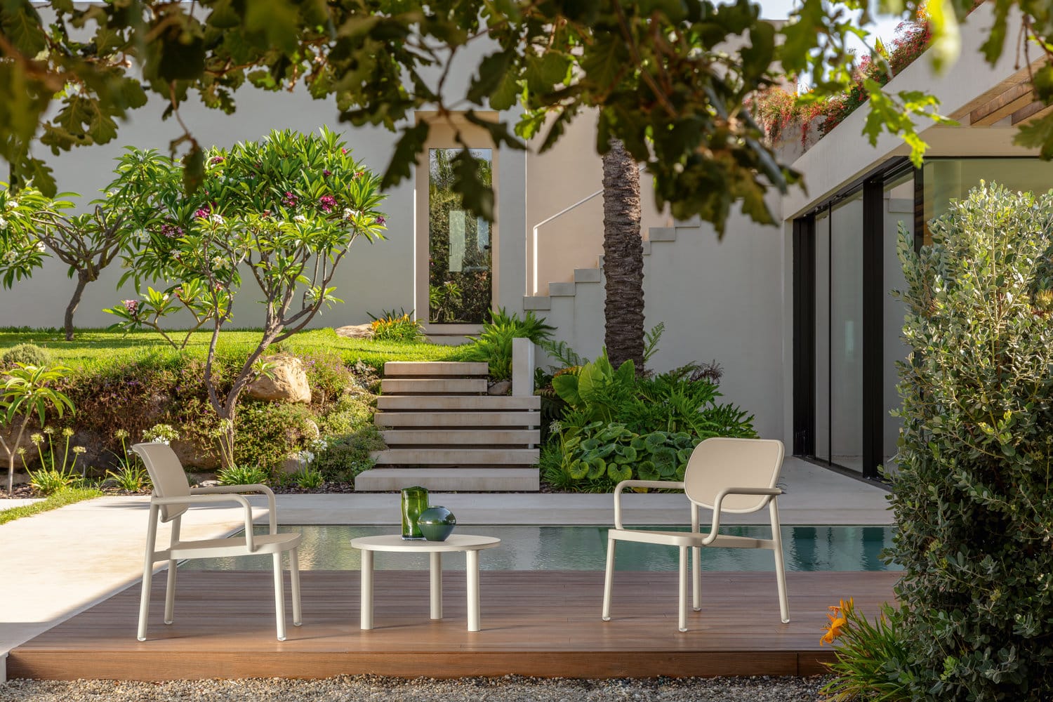 Salon de jardin extérieur design avec chaises beiges et table basse moderne près d’une piscine